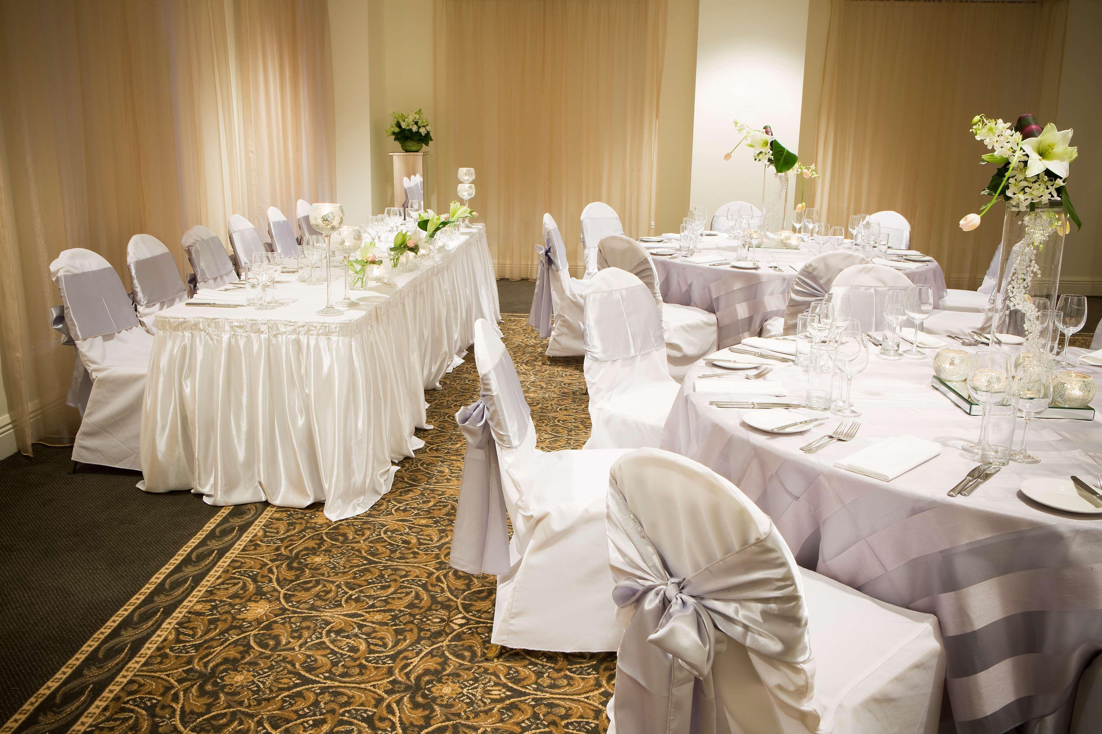 Stamford Plaza Melbourne Ξενοδοχείο Εξωτερικό φωτογραφία The photo depicts an elegantly set dining area, likely for a special event or celebration. There are several round tables covered with tablecloths, each set with plates, glassware, and cutlery. The chairs are dressed in white covers, some adorned wit