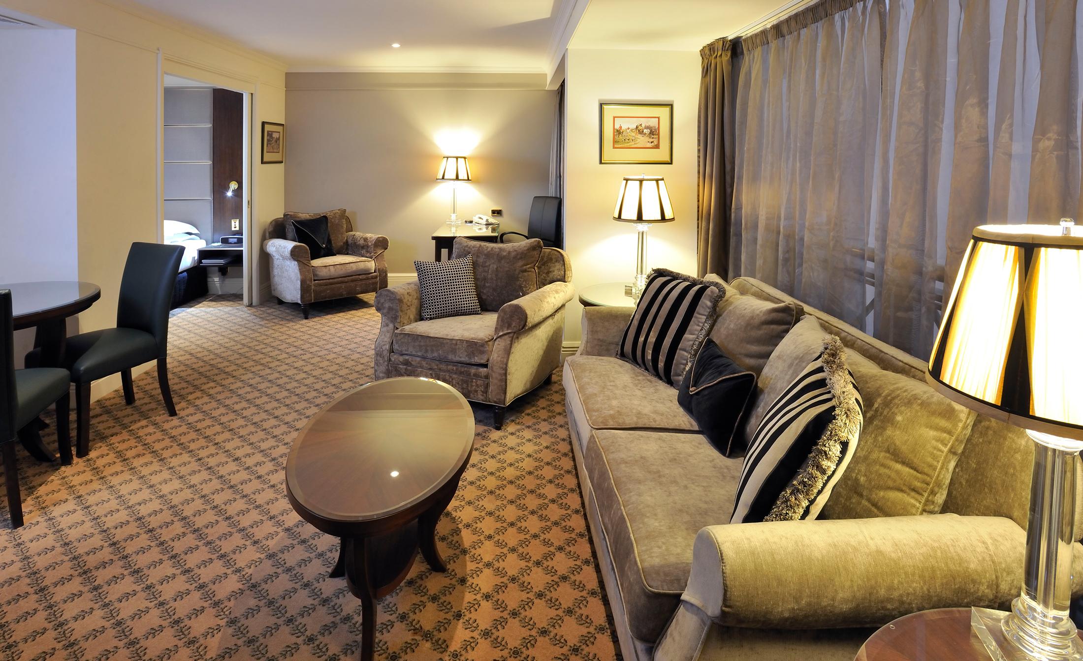 Stamford Plaza Melbourne Ξενοδοχείο Εξωτερικό φωτογραφία The photo shows a stylish and comfortable living area. It features plush seating, including a sofa with decorative cushions and a couple of armchairs. There's a circular coffee table in the center of the seating arrangement. The room has soft lightin