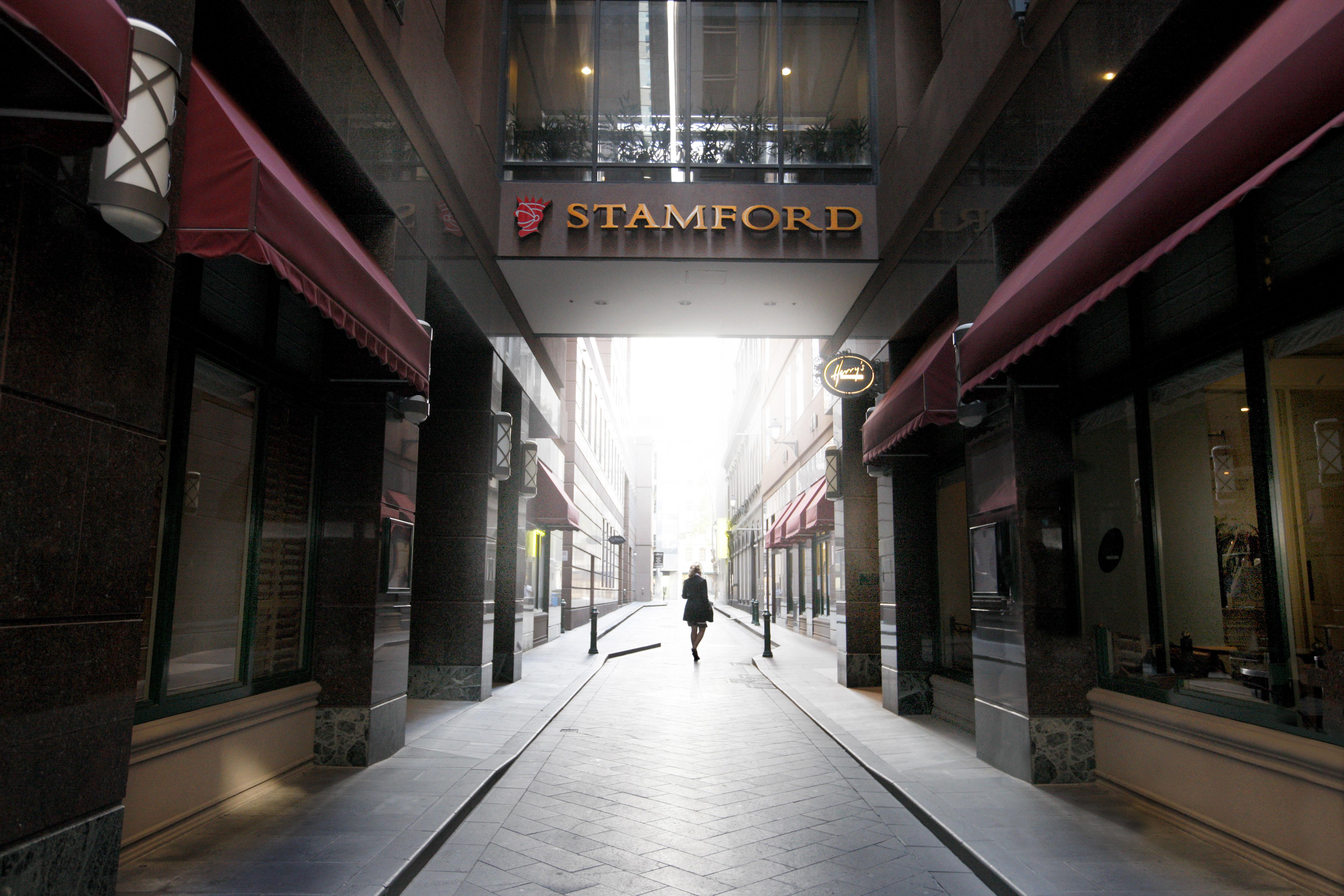 Stamford Plaza Melbourne Ξενοδοχείο Εξωτερικό φωτογραφία The photo depicts a narrow alley or passageway, possibly in an urban setting. On one side, there are storefronts with canopies, and on the opposite side, there is a prominent sign reading "STAMFORD." The pathway is lined with buildings, creating a se