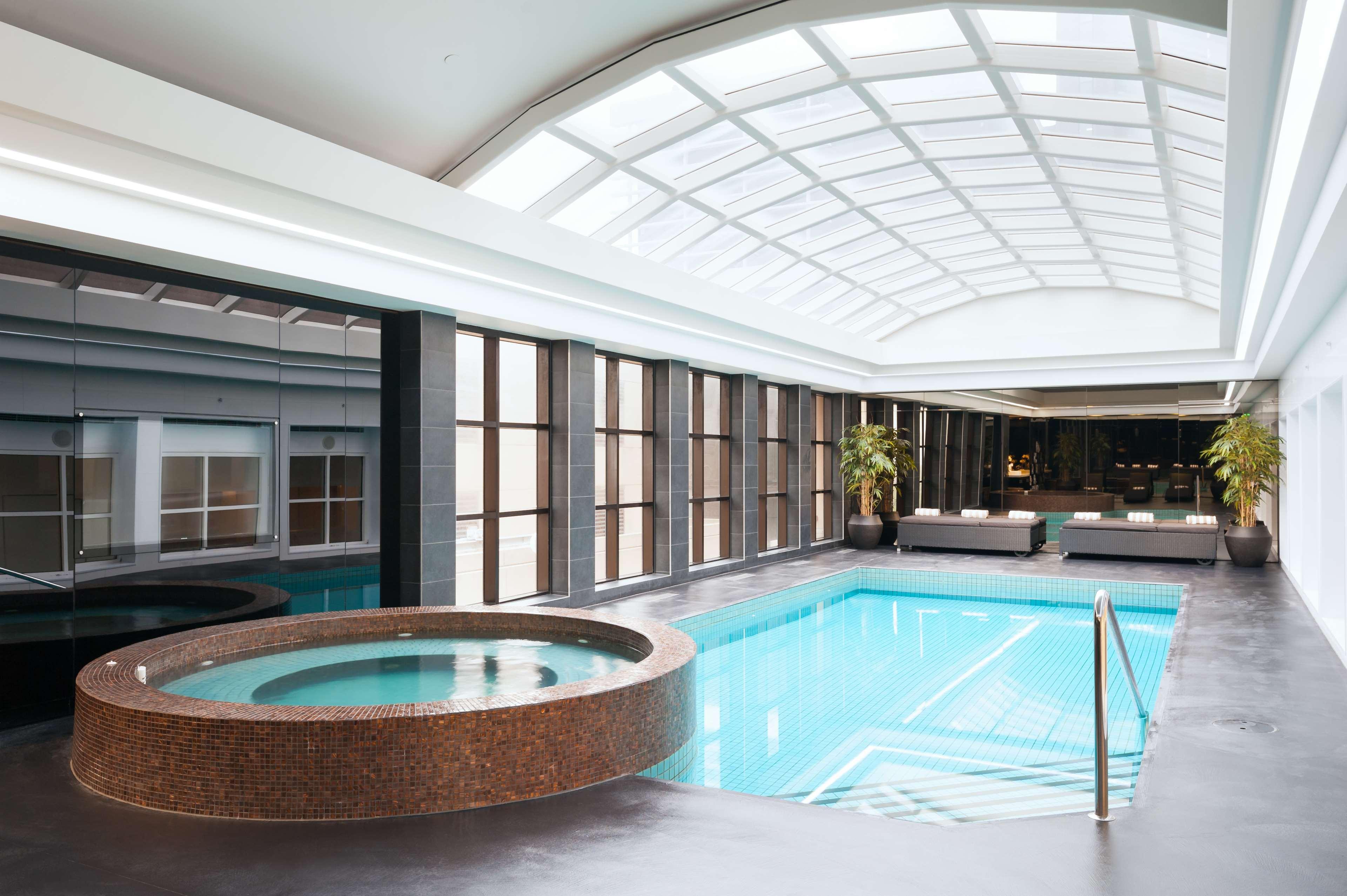 Stamford Plaza Melbourne Ξενοδοχείο Εξωτερικό φωτογραφία The photo shows an indoor swimming pool area. The pool is rectangular and has clear blue water, surrounded by a sleek, modern design. On one side, there is a round hot tub made of dark stone. Large windows line the walls, allowing natural light to fi