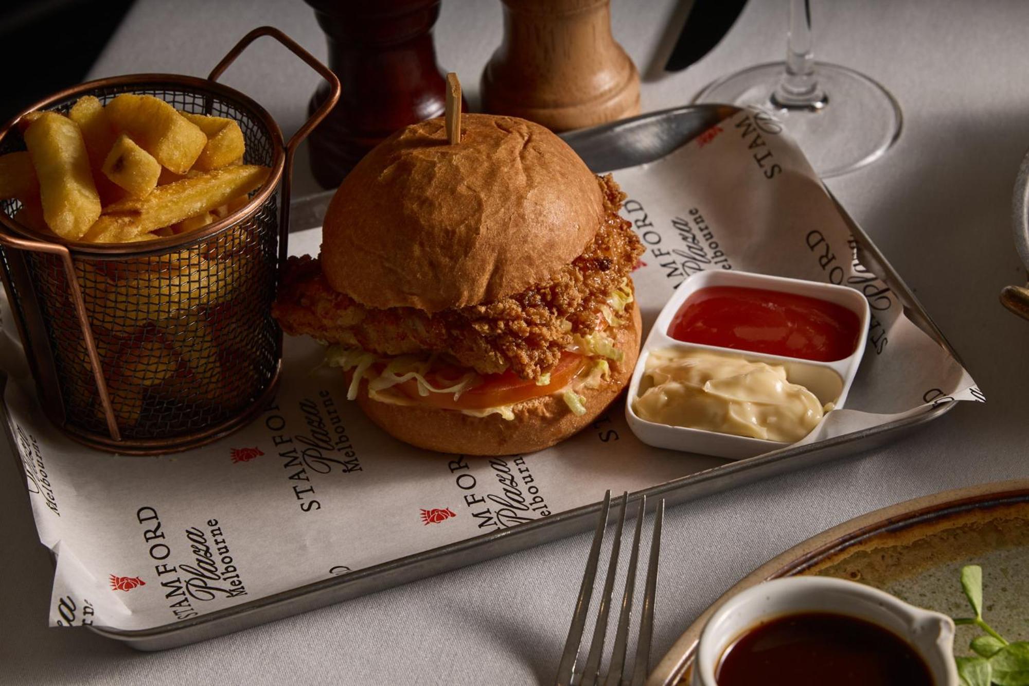 Stamford Plaza Melbourne Ξενοδοχείο Εξωτερικό φωτογραφία The photo features a meal served on a tray. In the center is a sandwich made with a golden-brown chicken fillet that appears crispy, placed inside a soft bun. The sandwich is likely complemented by some type of sauce or condiments underneath the chic