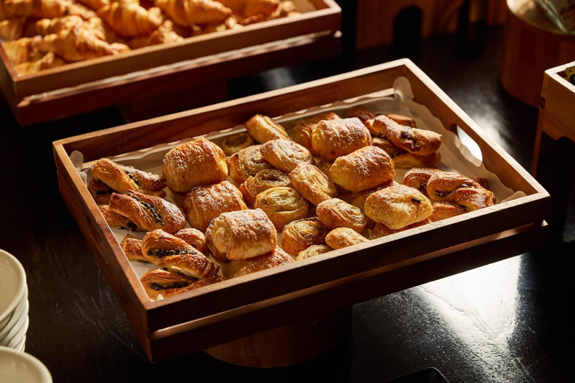 Stamford Plaza Melbourne Ξενοδοχείο Εξωτερικό φωτογραφία The photo shows a wooden tray filled with an assortment of baked goods. There are various types of pastries, including small, flaky items that appear to be puff pastries, and possibly some filled with chocolate or fruit. The pastries are golden brown